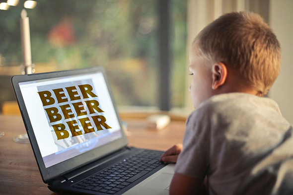 Junge vor Laptop mit Bier-Schriftzug