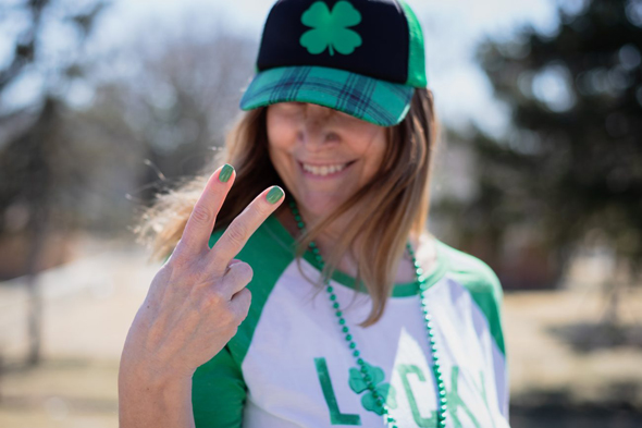 Frau in grüner Kleidung zeigt grüne Fingernägel vor