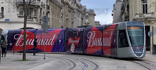 Fotografie einer mit Markenwerbung bedeckten Straßenbahn in Reims, mitten am Tag am 21.11.22