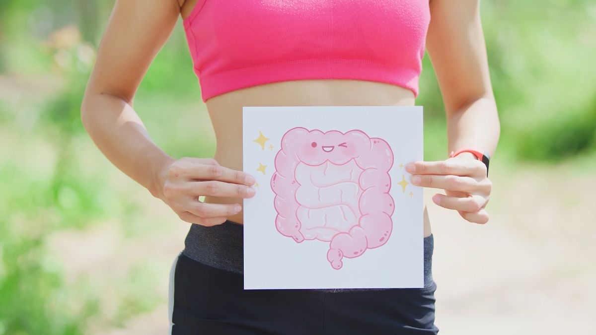 Frau hält eine Darmzeichnung vor ihrem Bauch