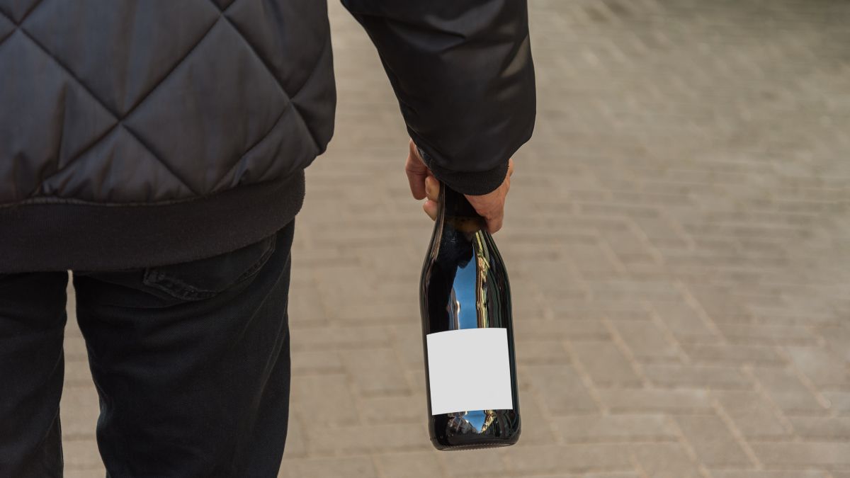 Mann trägt Flasche mit leerem, weißem Etikett