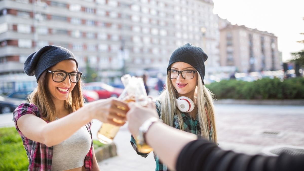 Drei junge Menschen stoßen auf der Straße miteinander an