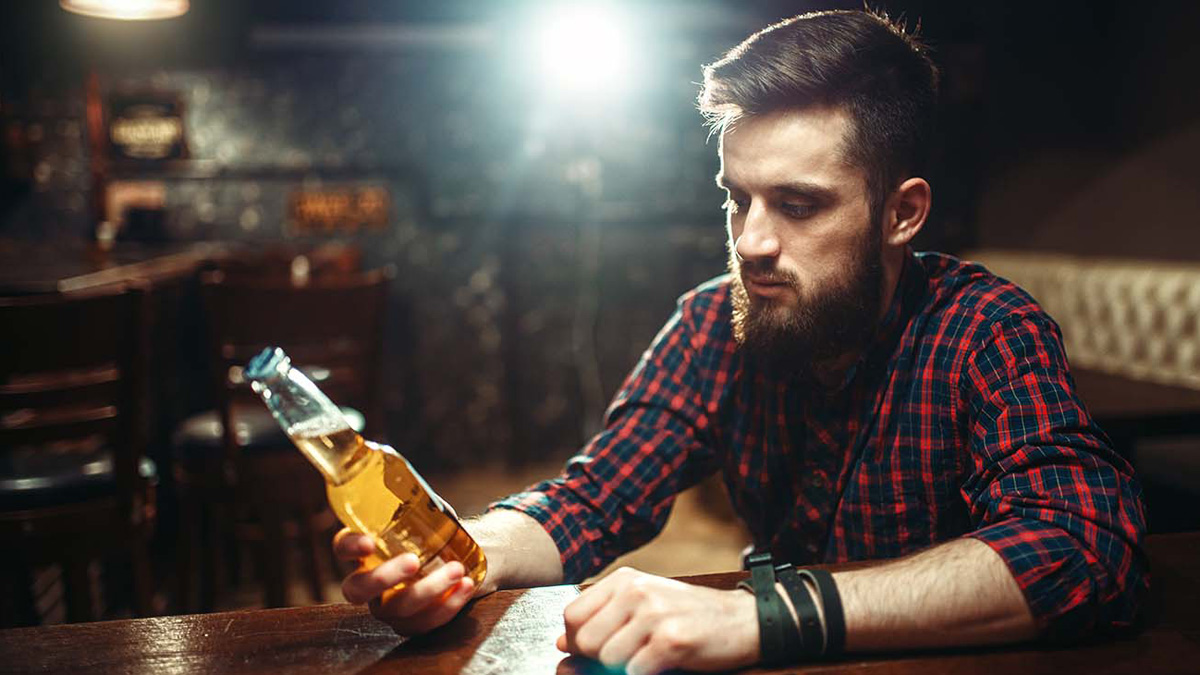 Mann in Bar mit Bierflasche