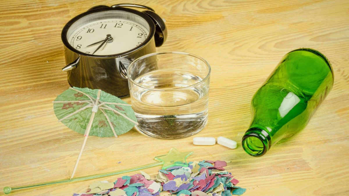 Wecker, Wasserglas, Pillen, leere Flasche auf Tisch