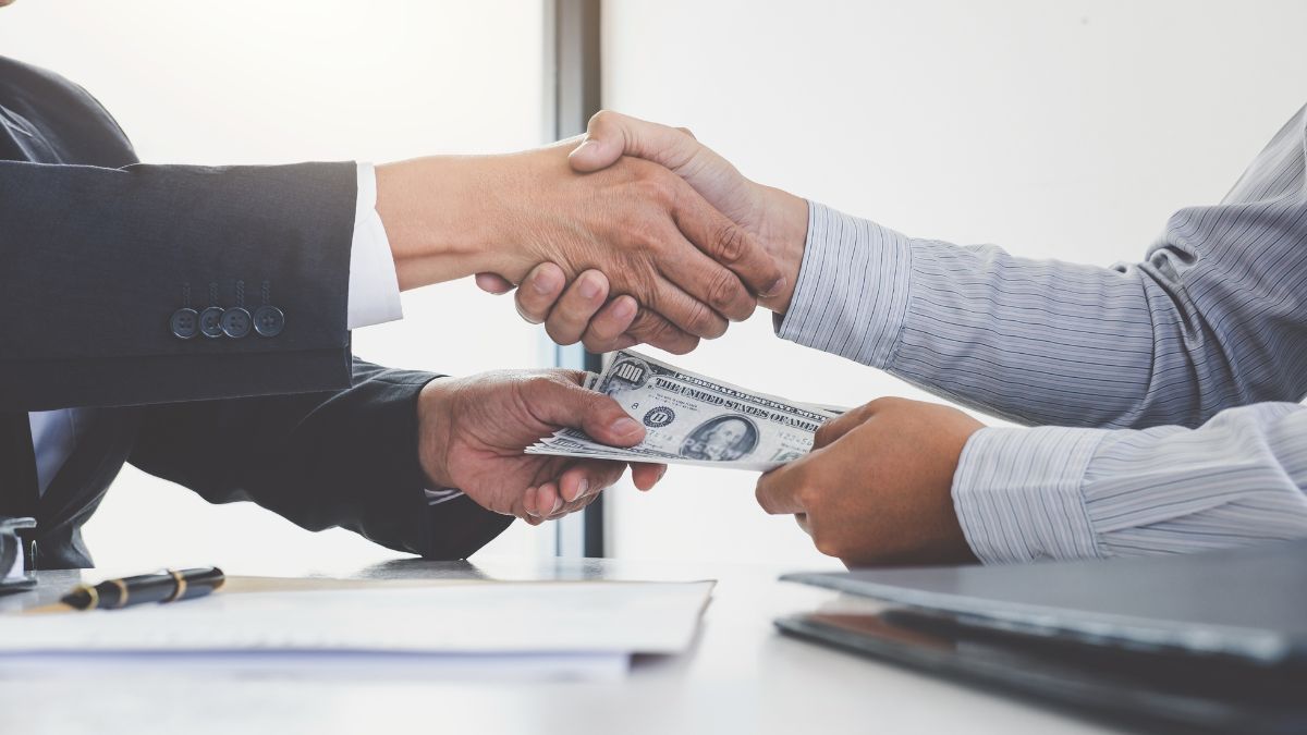 Händeschütteln zweier Männer bei Übergabe von Dollarnoten