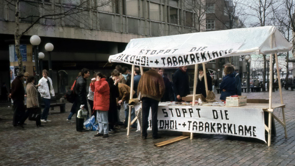 Infostand der Guttempler-Jugend 1986 auf dem Gerhart-Hauptmann-Platz in Hamburg mit Transparenten, die die Aufschrift 'Stoppt die Alkohol- und Tabakreklame' tragen