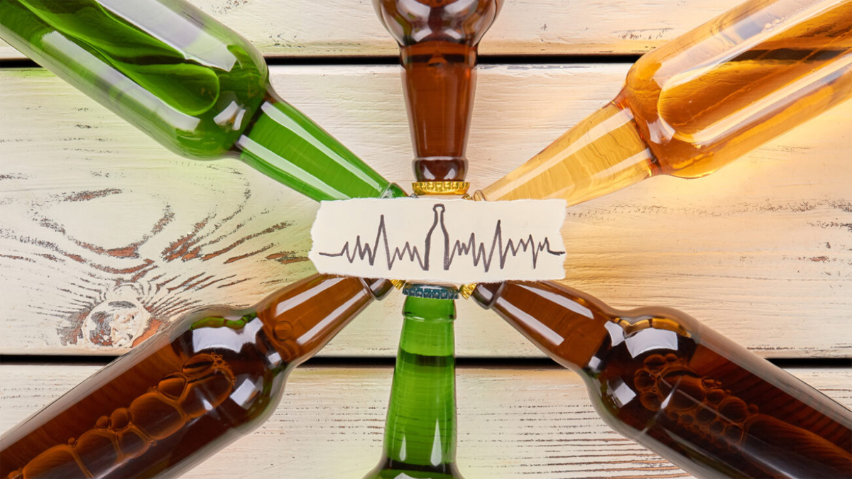 Sechs sternförmig angeordnet liegende Bierflaschen, darüber eingeblendet eine Herzrhythmuskurve