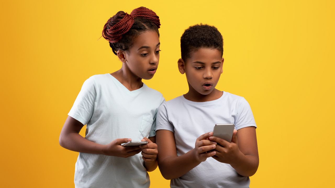 Ein Junge und ein Mädchen blicken schockiert auf ein Smartphone in der Hand des Jungens.