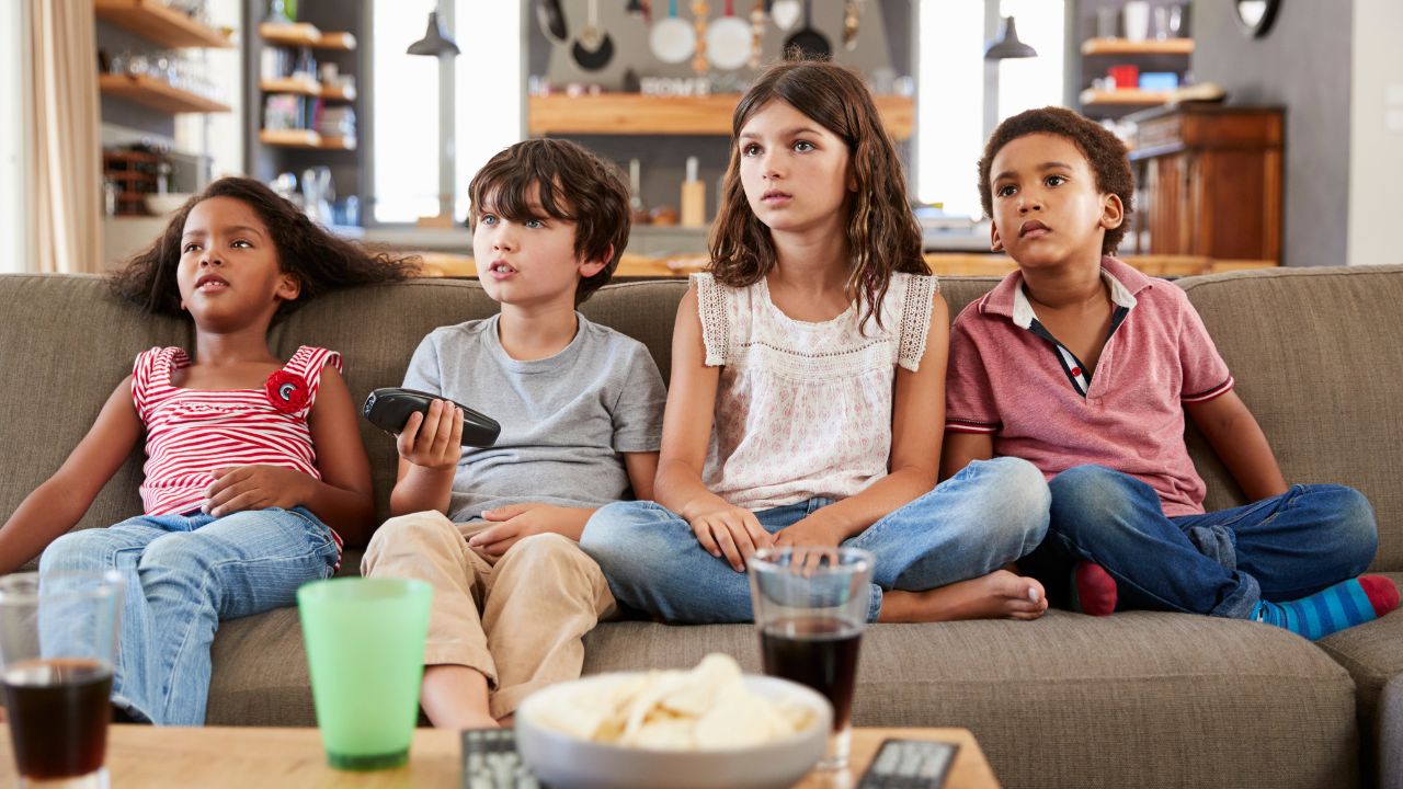 Vier Kinder auf einer Couch beim Fernsehen.