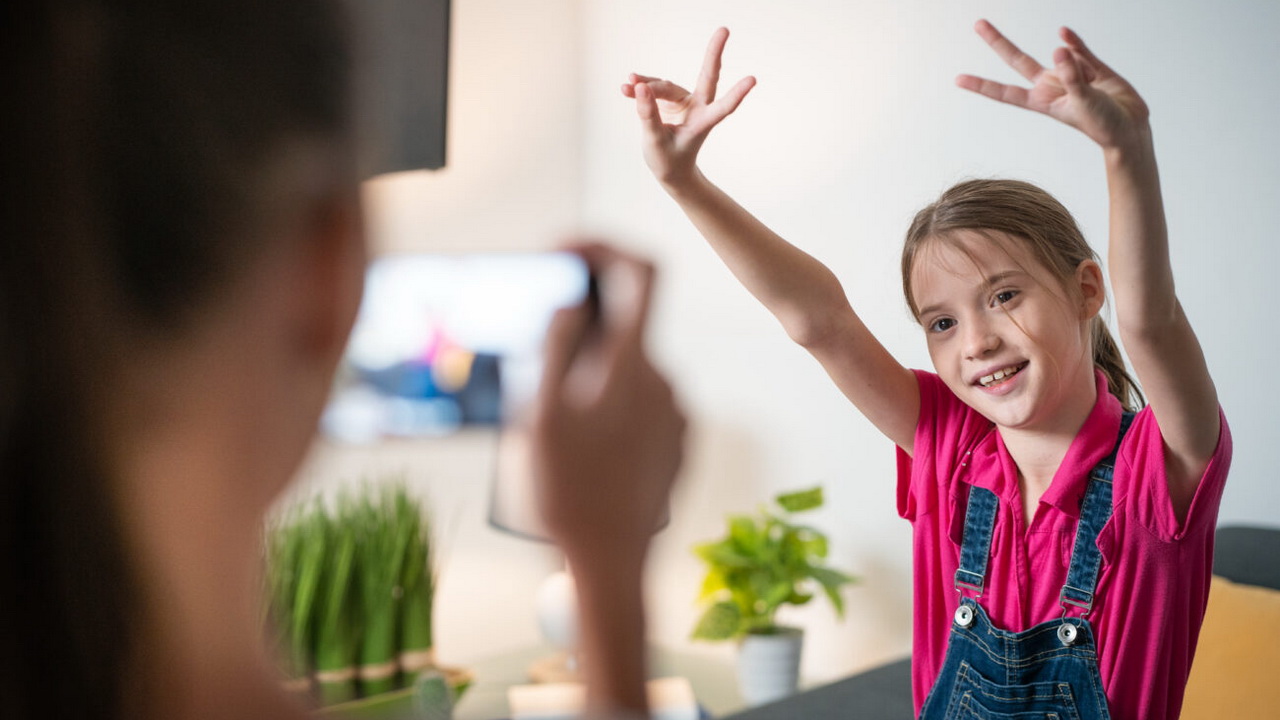 Mädchen filmt kleine Schwester mit Smartphone.