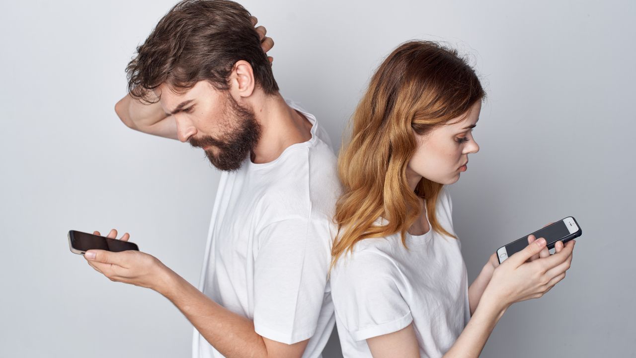 Mann und Frau mit Smartphones stehen Rücken an Rücken und schauen zweifelnd und unzufrieden aus.