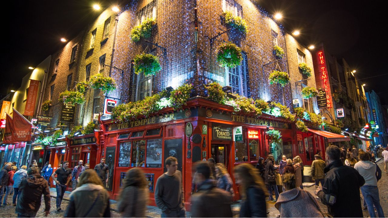 Fußgänger*innen vor Bar in Dublin bei Nacht.
