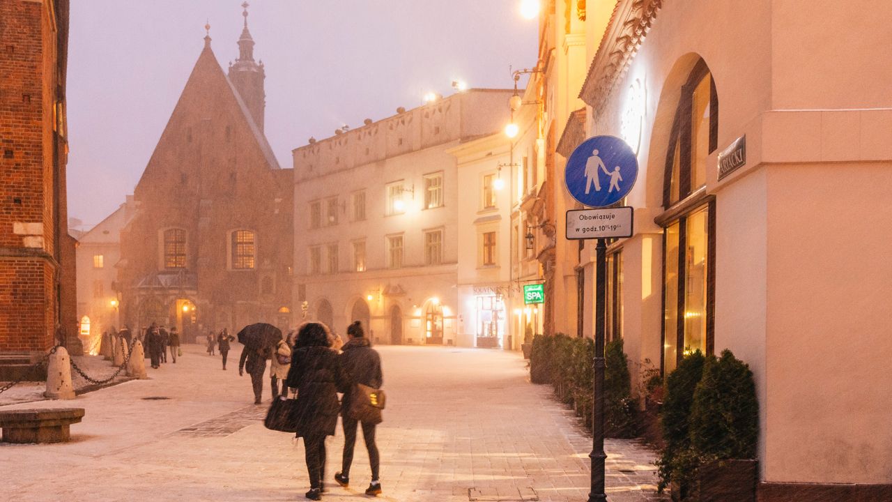 Fußgänger*innen in der abendlich beleuchteten Krakower Innenstadt.