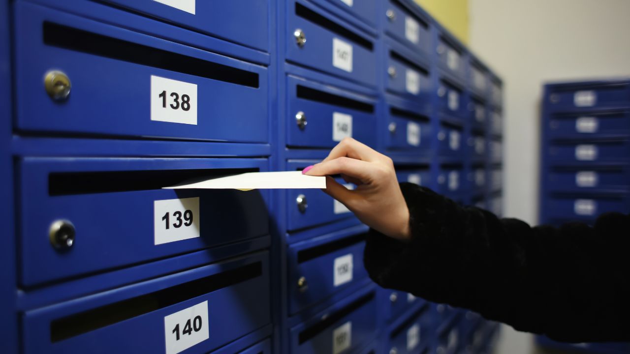 Frau wirft Brief in Briefkasten.