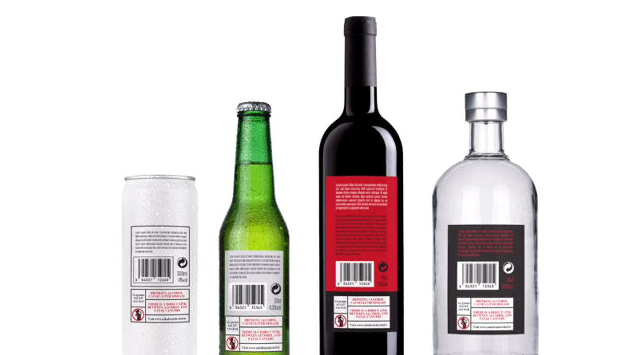 Rückansicht von vier alkoholischen Getränken (Dose, Bierflasche, Weinflasche, Spirituosenflasche) mit deutlich sichtbaren Barcodes, Mengenangaben und Warnhinweisen zum Alkoholkonsum auf den Etiketten vor weißem Hintergrund.