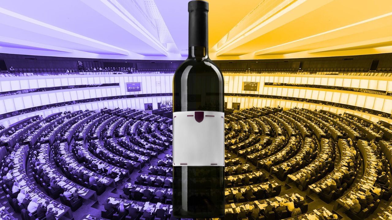 Eine dunkle Weinflasche mit leerem Etikett steht zentral im Vordergrund vor dem Plenarsaal des Europäischen Parlaments, der farblich in Blau (links) und Gelb (rechts) zweigeteilt ist.