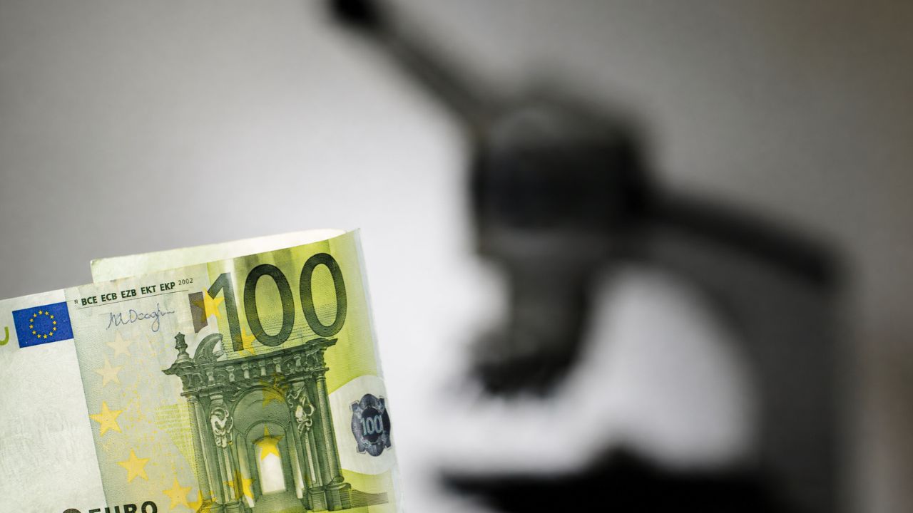 100-Euro-Schein im Vordergrund, unscharfes Mikroskop im Hintergrund als Symbol für Forschungsfinanzierung.