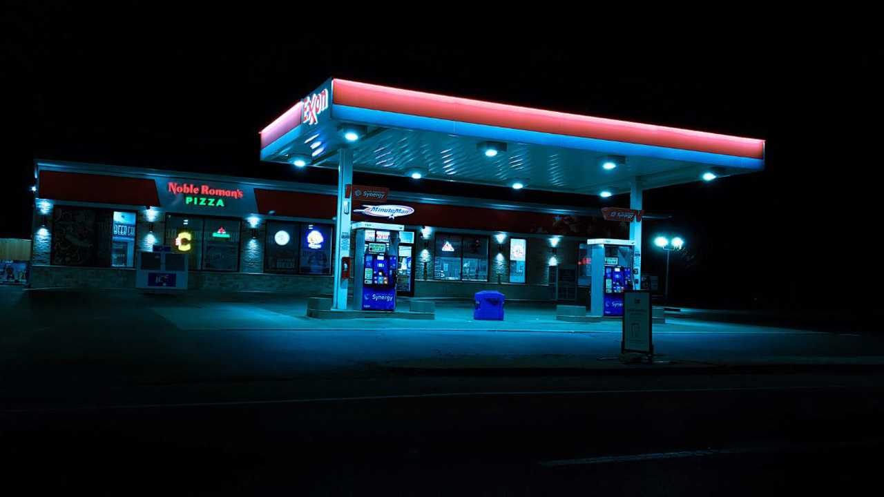 Menschenleere Tankstelle mit blauer Neonbeleuchtung bei Nacht.