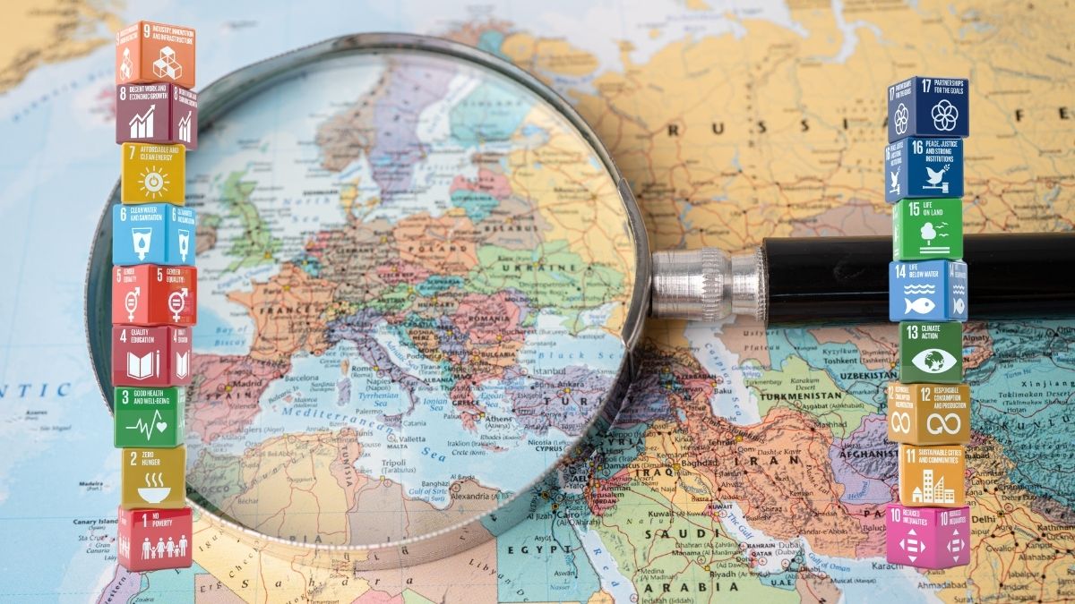 Europakarte unter Lupe - davor Stapel der Nachhaltigkeitsziele