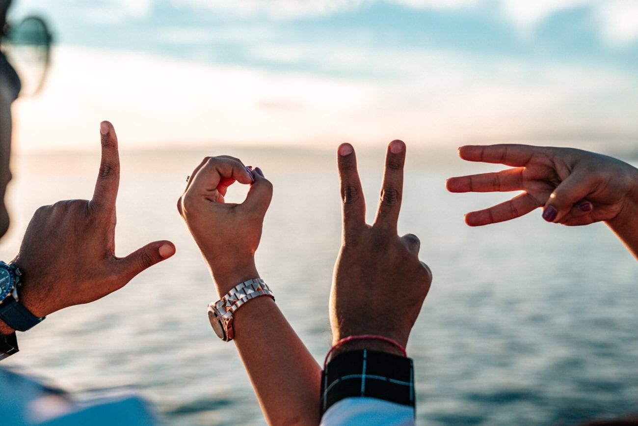 Vier Hände bilden mit den Fingern das Wort 'LOVE'.