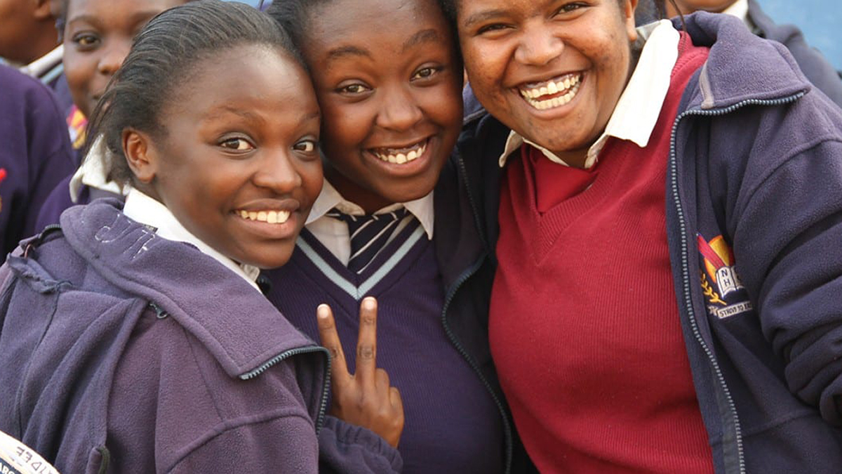 Drei afrikanische Schülerinnen lächeln in die Kamera